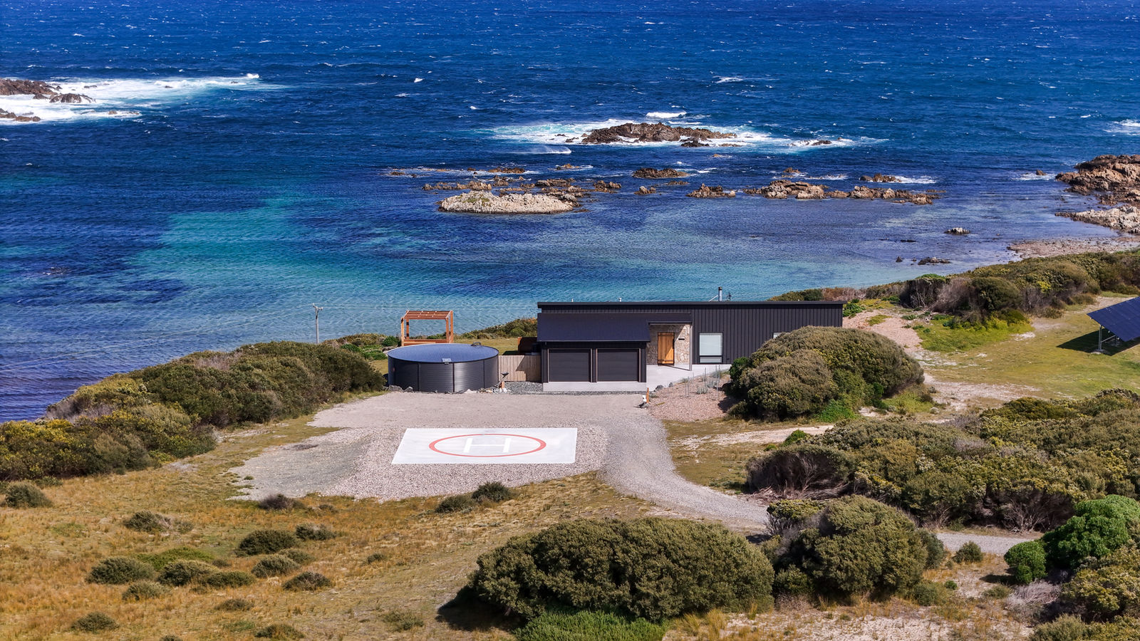 Aerial view of the villa and cedar hot tub above the rocky King Island shore