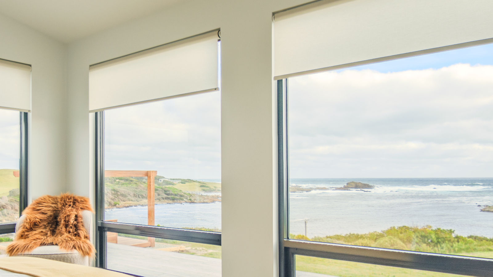 Bedroom with sheepskin throw and a window to the wild coastline